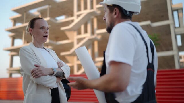 Construction professionals reviewing architectural plans with a female client while discussing progress on a residential building project. Real estate development and property construction concept.