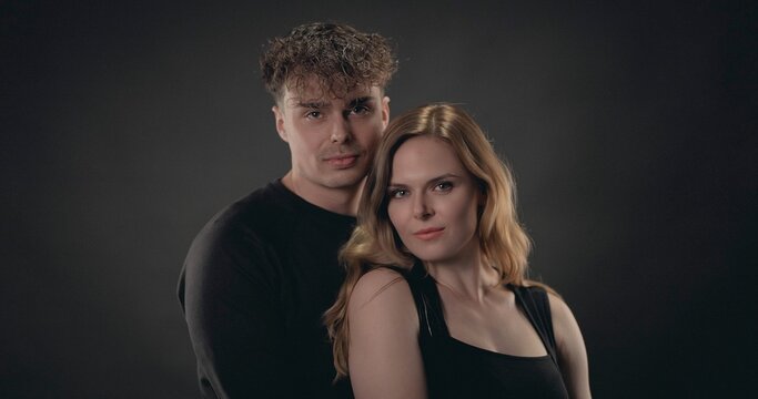 Young couple standing close, expressing connection and style on dark background