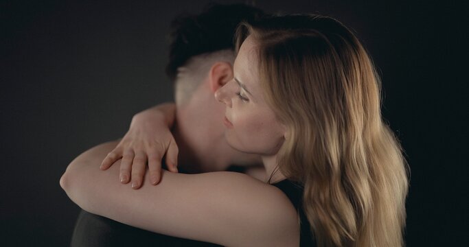 Couple sharing an intimate moment, hugging and feeling togetherness on a dark background