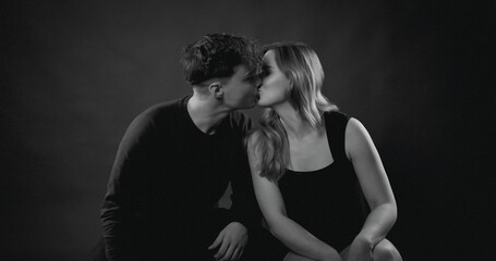 Fototapeta premium Romantic couple sharing an intimate kiss in a dark studio