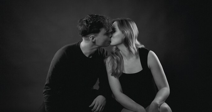 Romantic couple sharing an intimate kiss in a dark studio