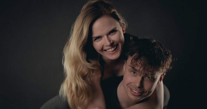 Happy couple posing together, a woman riding piggyback on a man, smiling
