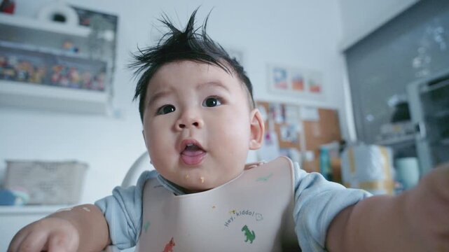 Asian baby boy self feeding sweet corn using baby led weaning method at home.
