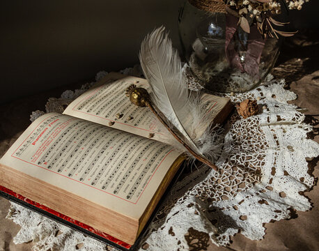 Vintage spiritual still life with antique hymn book, feather and dried bouquet