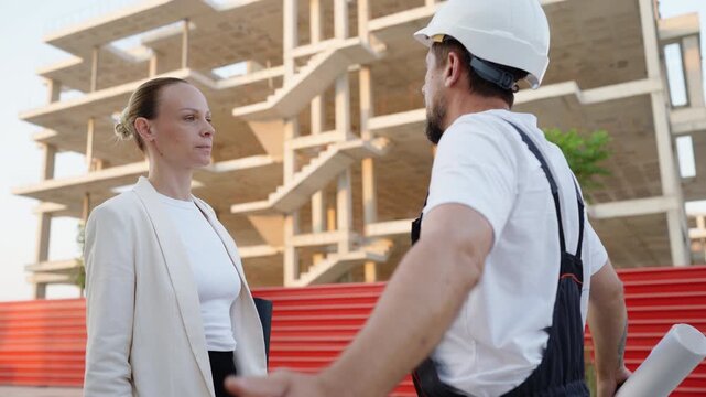 Frustrated female architect arguing with a construction foreman holding blueprints at a residential building site, discussing project delays, construction issues and workflow challenges.