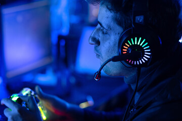 Male gamer is playing online video games or competing in esports, in a neon-lit gaming room © chomplearn_2001