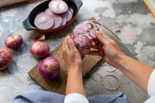 Hands peeling fresh red onions