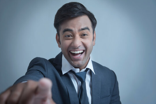 Young businessman smiling pointing at camera