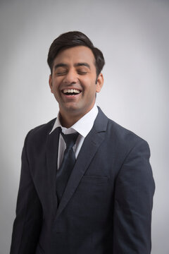 Smiling businessman closing eyes making face