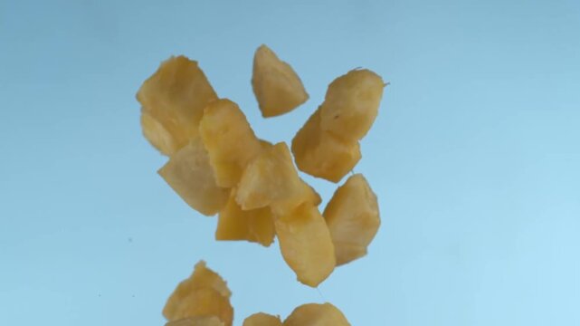 Floating chunks of fresh juicy yellow pineapple on light blue background