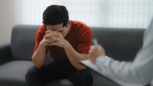 PTSD, Sad man with psychologist taking notes during therapy session