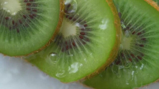 Refreshing water splashes over juicy green kiwi fruit slices