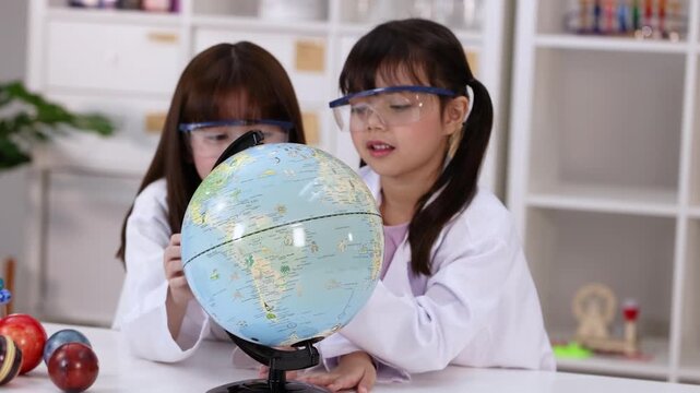 Two Young Girls in Lab Coats Studying a World Globe