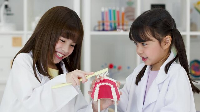 Young Students in Lab Coats Practicing Dental Hygiene with Teeth Model