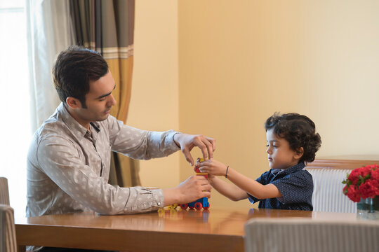 Father helps young son play with building blocks