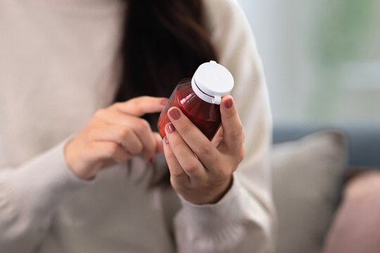 Asian woman checking on medicine bottle at home