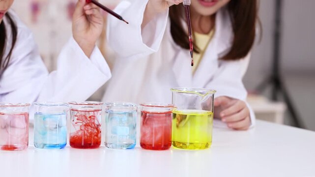 Children in Lab Coats Conducting Chemistry Experiment with Colorful Liquids