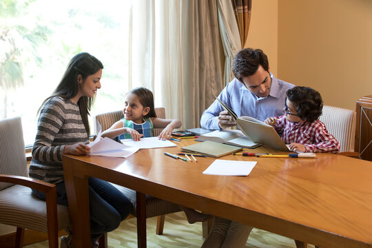 Mother and father helping daughters with homework