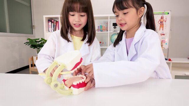 Elementary Students in Lab Coats Learning Dental Hygiene with Teeth Model