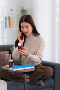 Asian woman checking on medicine bottle at home