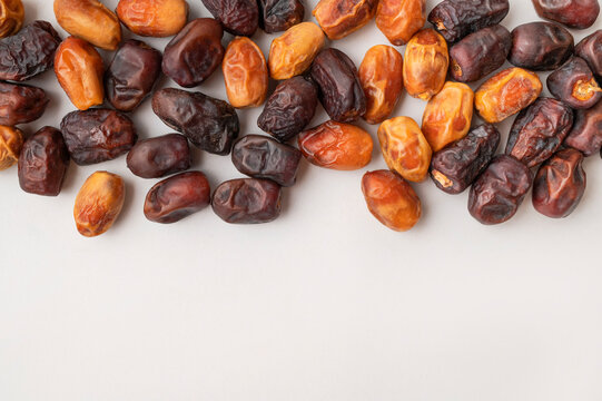 Sweet dried fruit snack scattered on light gray surface, assorted dates shown from top view with clean copy space. Snack imagery suits healthy food campaigns, retail packaging and lifestyle marketing.