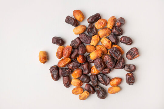 Sweet dried fruit snack scattered on light gray surface, assorted dates shown from top view with clean copy space. Snack imagery suits healthy food campaigns, retail packaging and lifestyle marketing.