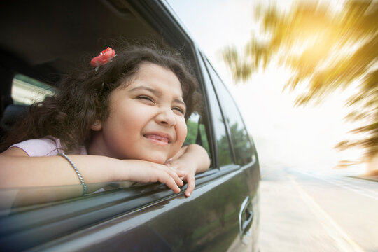 Smiling girl looking out car window 