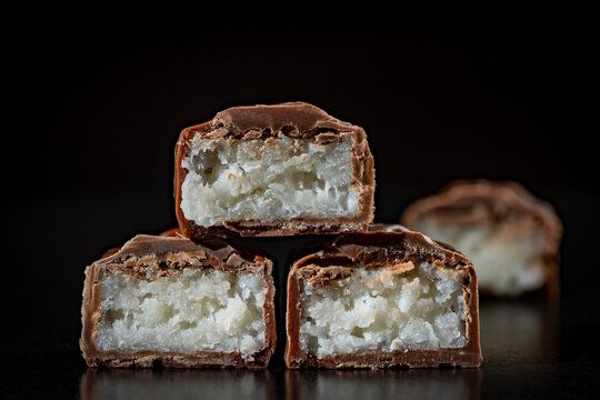 Closeup of cut coconut chocolate bars showing rich white flake filling covered in milk chocolate. Perfect for sweet snack marketing, confectionery branding, and dessert menu designs