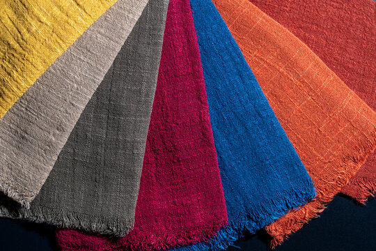Top view of multicolored linen textile swatches arranged in fan shape showing natural texture and fringed edges, closeup. Ideal for interior design, fashion marketing, and home decor concepts