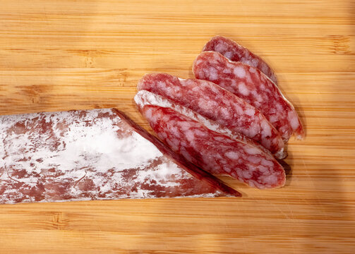 Sliced fuet sausage on wooden board closeup