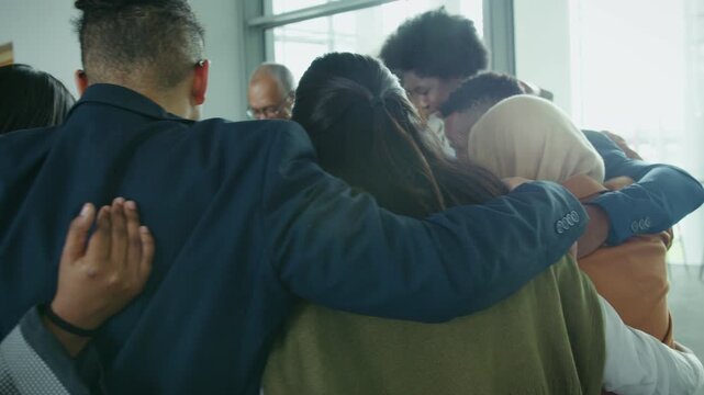 A diverse group of professionals huddle together, embracing unity, support, and collaboration. They demonstrate strong teamwork and community in a positive corporate environment.