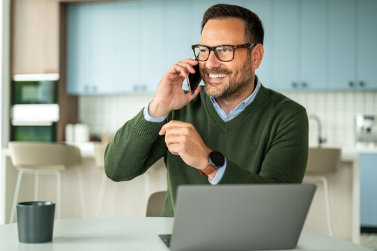 Professional businessman telecommuting, communicating on cell phone, managing work remotely from a casual workspace, making a successful business call, working online