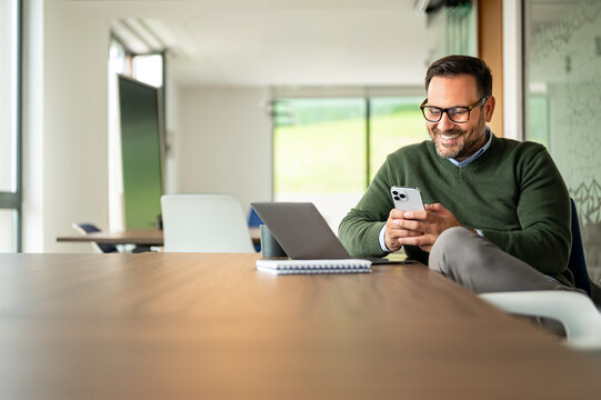 Professional man messaging on mobile device, communicating and networking online, connecting with colleagues for business in an office setting