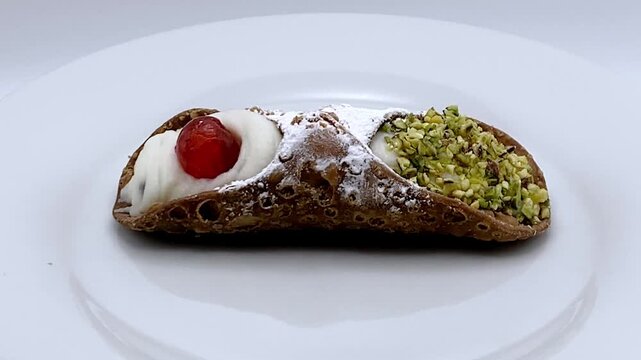 Sicilian cannolo pastry filled with sweet ricotta and topped with cherry and pistachios isolated on white background. Studio shot 4K.