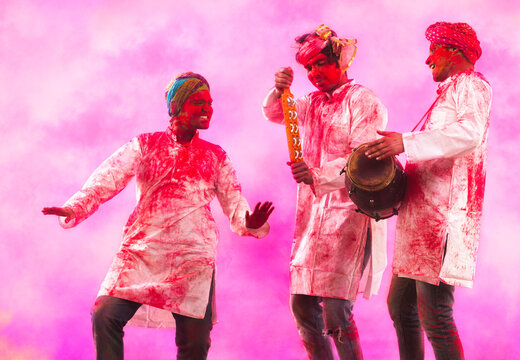 Three Young Indian men With Colored Face Dancing During Holi Color festival