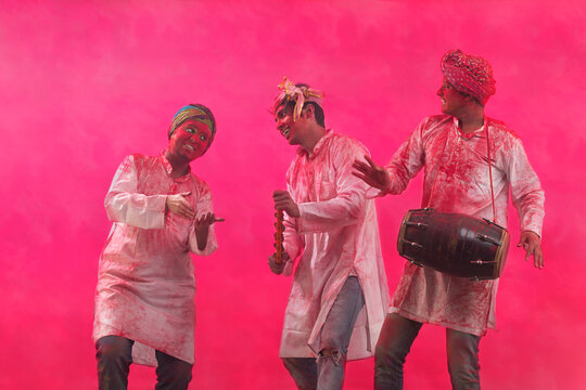 Three Young Indian men With Colored Face Dancing During Holi Color festival
