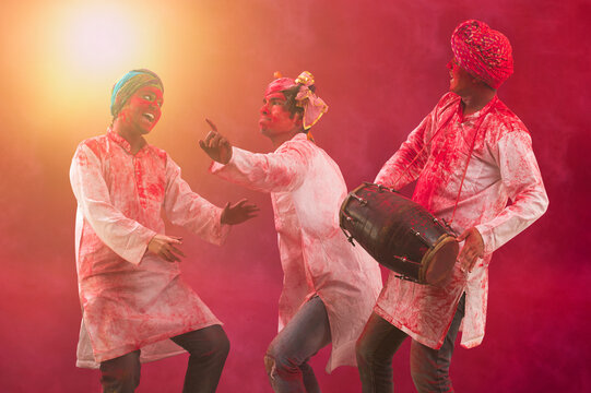 Three Young Indian men With Colored Face Dancing During Holi Color festival