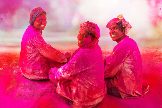 Young Indian Men sitting on floor,covered in colored powder during holi color festival
