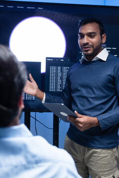 Programmer team collaboration, working on coding task, reviewing code while Male Programmer presenting code in the screen in tech office.