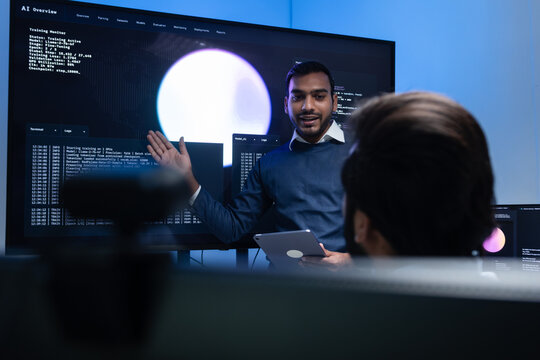 Indian male Software Engineer, Developer working with Team, Looking at Monitoring, Presenting coding, data, AI Machine Learning Model to Colleague, Discussion, Reviewing and Brainstorming together.