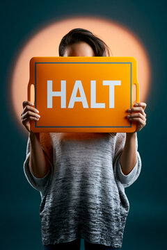 Kind h&auml;lt oranges Schild mit Aufschrift Halt vor dunklem Hintergrund