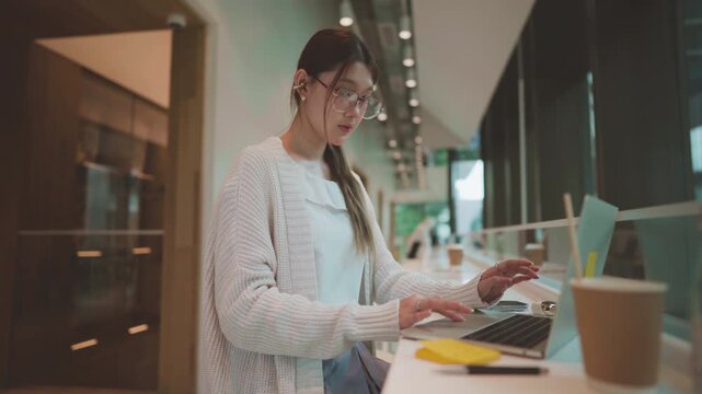 Young adult business asian woman using laptop wear eyeglasses using pen writing sticky note