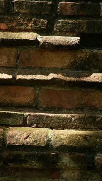 Vertical rustic background of an old brick wall with weathered texture, dark shadows and warm sunlight, ideal for architecture, vintage and natural design use.