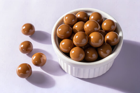 Caramel Chocolate Candy Balls in Bowl, Glossy Brown Sweet Spheres, Chocolate Covered Caramel Treats, Shiny Malt Ball Candies, Round Caramel Chocolates Bowl