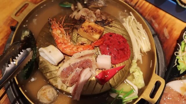 Top view of the traditional asian grill or hot pot in Thail restaurant cooking seafood and meat