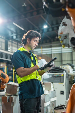 man engineer inspecting robotic arm with digital tablet in smart factory, focusing on automation, preventive maintenance, quality control, advanced manufacturing and Industry 4.0 operations.