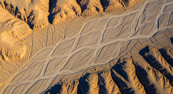 Aerial view of intricate braided dry riverbed patterns and eroded canyon formations in an arid desert landscape