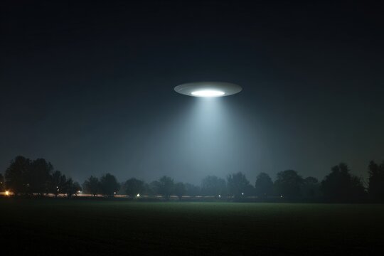 A UFO hovers over a dark field, casting a bright beam of light below.