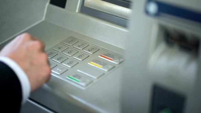 Man entering pin code on ATM machine key pad making mistake and pressing correction button in 4K Ultra HD footage
