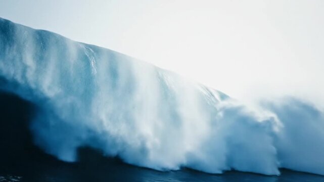 A dramatic and powerful blue ocean wave crests and breaks, showcasing the immense force and beauty of the sea with a cascade of white foam and spray